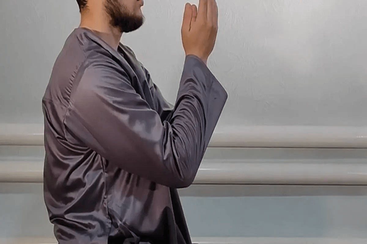 A Muslim man in grey thobe making dua